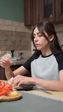 Young woman preparing tortilla wrap with vegetables in home kitchen vertical video footage