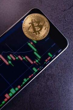 Golden bitcoin coin on smartphone with bitcoin trading chart