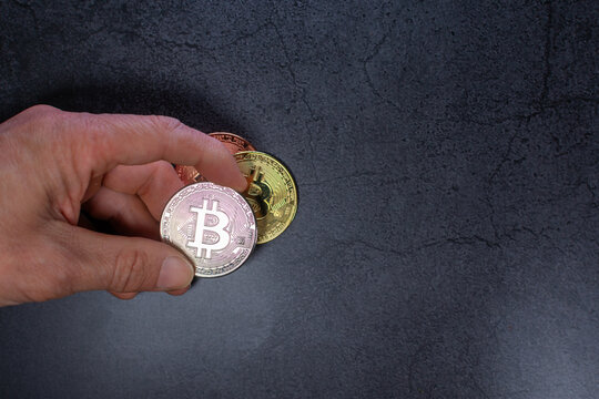 Man hand holding silver bitcoin coin on dark granite surface