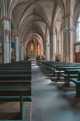 Teilansicht innen Kirchenraum mit Bänken und Gewölbe mit Lampenlicht