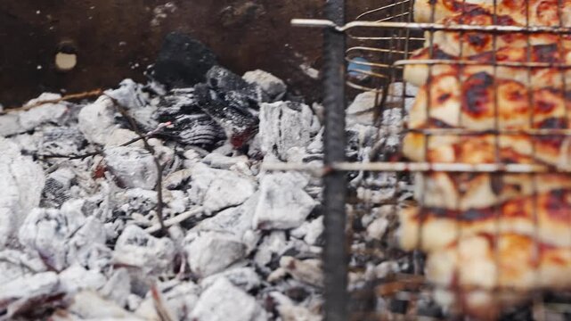 Cooking meat on a grill with charcoal at an outdoor gathering