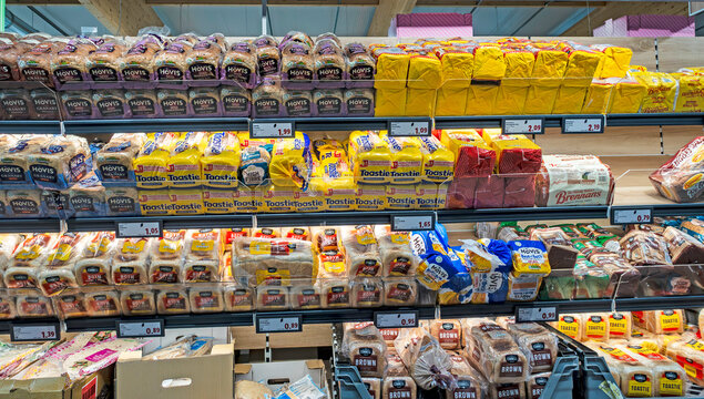 Shelves stocked with various brands of sliced bread, including Hovis and Brennans, at a grocery store in Dublin, Ireland.