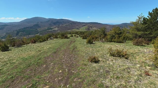 Sunlit path winds through grassy hillside. Mount Goc, Ljukten peak. Balkans, Serbia