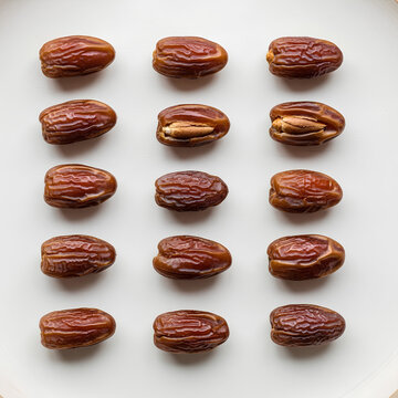 Closeup of a collection of fresh ripe dates on a white plate.