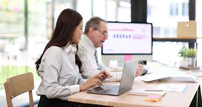 Business colleagues collaborating on a project, analyzing data in a modern office, junior worker learning from senior manager while discussing financial reports and strategy
