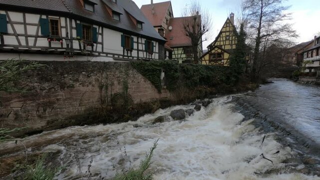 The Weiss river running between half timbered houses, Kaysersberg, Alsace, France, Europe. River with strong current flowing through the rocks.