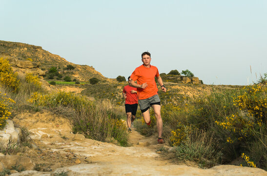 Men trail running outdoors on challenging mountain path