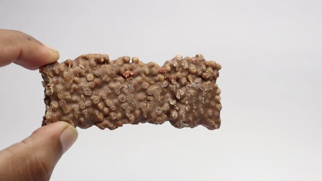 Energy bar or the granola bar held in the hand on a white background