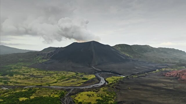 Mount Yasur erupting on Tanna Island, Vanuatu, belching smoke and ash over dark volcanic slopes and vibrant green vegetation near Port Resolution, dramatic coastal landscape. Aerial view drone flight