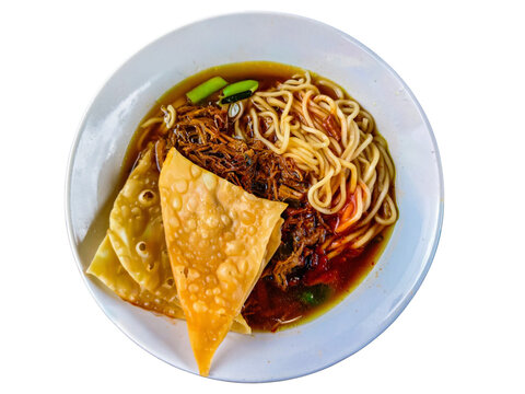 Indonesian chicken noodle bowl or Mie Ayam with fried wontons and savory gravy isolated on white background.
