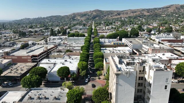 Whittier, California, USA - Aerial Pullback View of Uptown Greenleaf Promenade Downtown Area With Mountains and Commercial Buildings