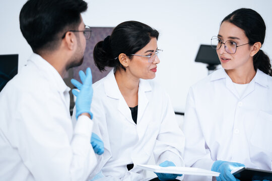Group of scientist in medical uniform talk and discuss research project in laboratory. Medical professional team collaborate on biotechnology experiment result and clinical data analysis in lab