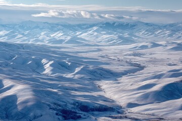 Fototapeta premium Expansive snow-covered mountain valleys under a crisp, cloudy sky