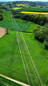 Drone flying above power lines and green farmland
