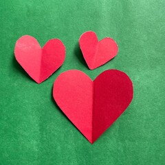 Obraz premium Three colorful hearts on green background