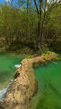 Turquoise water flows through mossy stones. Bigar Waterfall, Serbia. Vertical