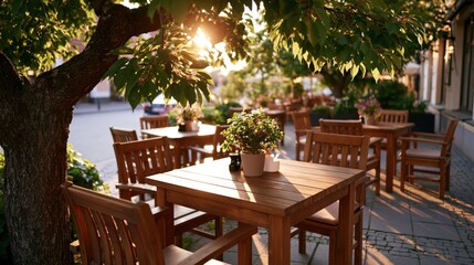 Obraz premium Golden hour sunlight filters through tree leaves onto an empty outdoor cafe terrace