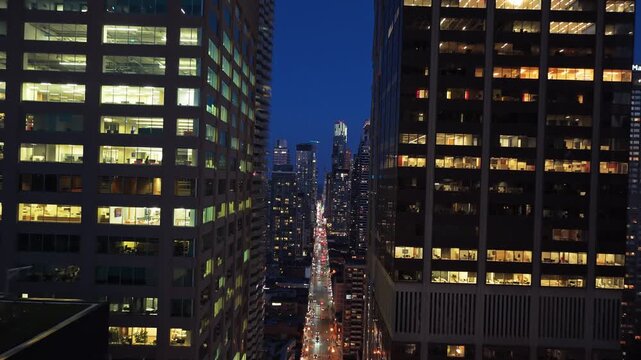 Dutch tilt perspective between modern office buildings into canyon of skyscrapers revealing urban street scene with heavy traffic in downtown Toronto at night