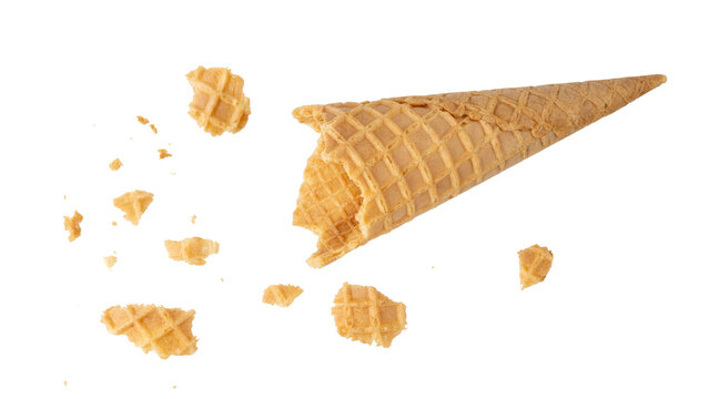 Empty crispy baked waffle cone for ice cream with crumbs flying isolated on white.