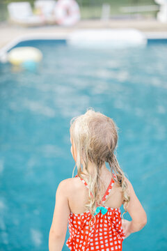 Blonde child on diving board looking at pool 