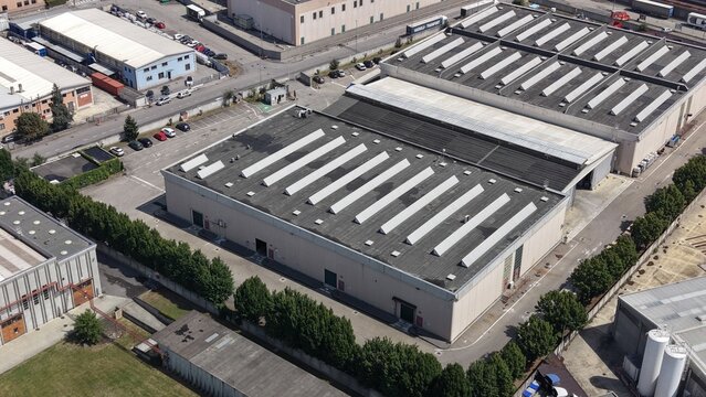 Aerial drone view of a large industrial area near Milan, Italy. Warehouses, factories and logistics buildings create a modern commercial landscape.