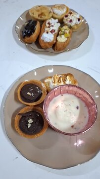 Close up of a Selection of Eclairs Arranged on Plates. Vertical Video of Delicious Pastries with Various Toppings and Flavors