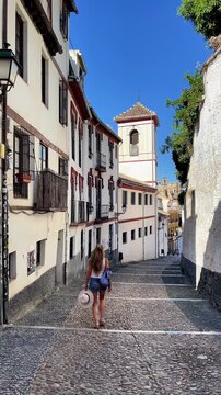 young woman walking down a historic cobblestone street in Albaicin, Granada in Spain