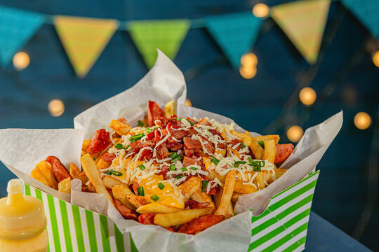Dramatic Low Angle Shot of Towering Loaded Fries with Cheddar, Bacon and Sausage at Night Fair
