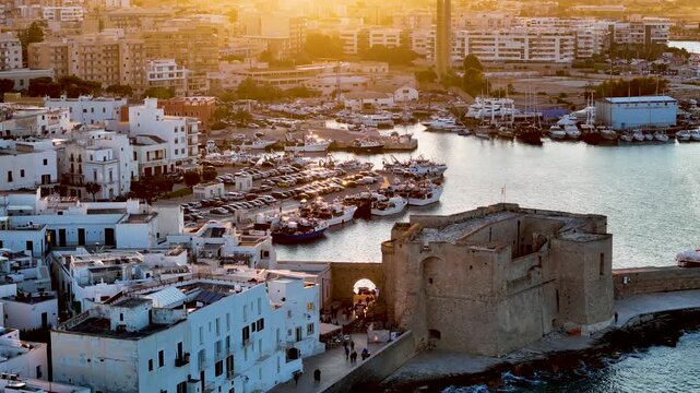 Aerial 4K drone video footage with panorama view of Monopoli Old Town at sunset, scenic Adriatic sea coastal cityscape in Puglia with historic Italian architecture