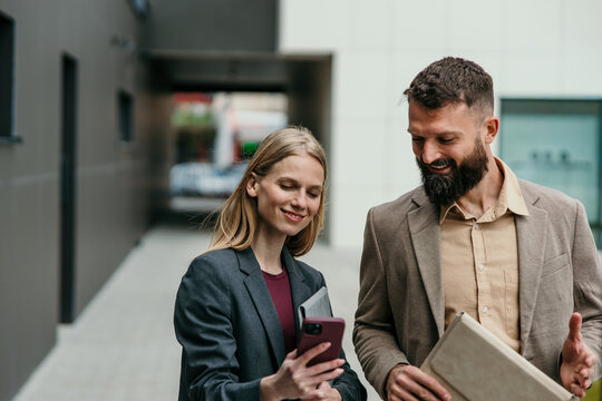 Business colleagues collaborating on smartphone outdoors