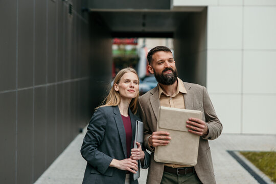 Business colleagues walking outdoors with documents