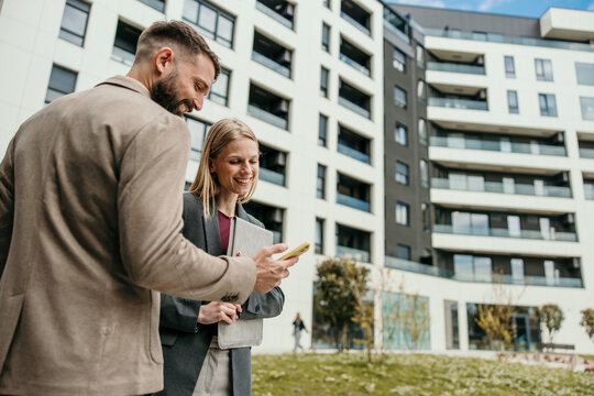 Business partners using phone consulting real estate outdoors