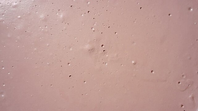 Top view time lapse shot of dark beige surface gradually drying, forming visible cracks and a fragmented texture resembling natural mudcracks