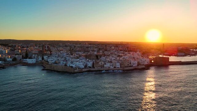 Aerial 4K drone video footage with panorama view of Monopoli Old Town at sunset, scenic Adriatic sea coastal cityscape in Puglia with historic Italian architecture