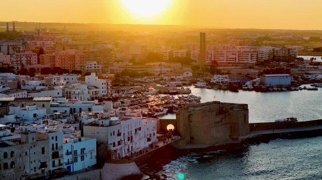 Aerial 4K drone video footage with panorama view of Monopoli Old Town at sunset, scenic Adriatic sea coastal cityscape in Puglia with historic Italian architecture