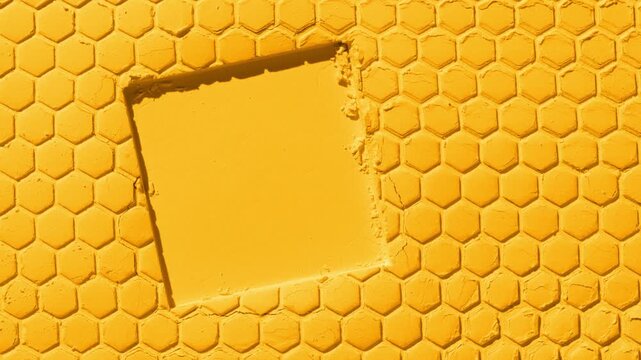 Overhead capture of a marigold powder surface with a small honeycomb pattern printed on it and a square imprint, lit with dynamic orbiting light that projects moving shadows