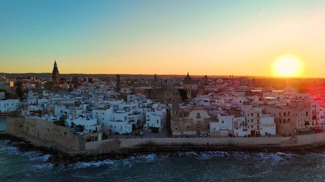 Aerial 4K drone video footage with panorama view of Monopoli Old Town at sunset, scenic Adriatic sea coastal cityscape in Puglia with historic Italian architecture