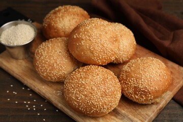 Naklejka premium Tasty baked buns with sesame seeds on wooden table, closeup