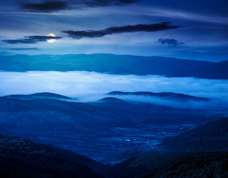 carpathian mountain landscape on a foggy night. outdoor adventure with stunning view. full moon over mountainous countryside of ukraine in summer. mysterious rolling hills
