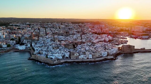 Aerial 4K drone video footage with panorama view of Monopoli Old Town at sunset, scenic Adriatic sea coastal cityscape in Puglia with historic Italian architecture