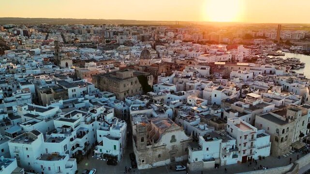Aerial 4K drone video footage with panorama view of Monopoli Old Town at sunset, scenic Adriatic sea coastal cityscape in Puglia with historic Italian architecture