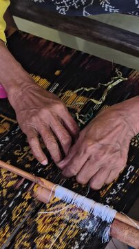 A weaver's hands tying a woven cloth