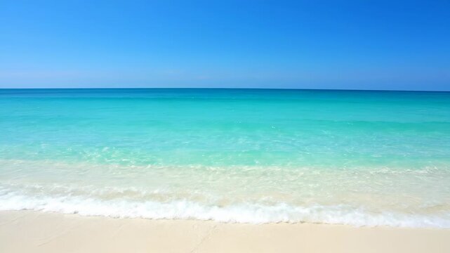 Turquoise ocean water gently laps against a white sand beach under a clear, blue sky