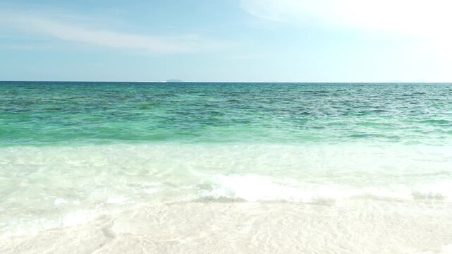 Serene Beach Scene with Clear Turquoise Water, Gentle Waves, and White Sand Under Bright Blue Sky and Horizon