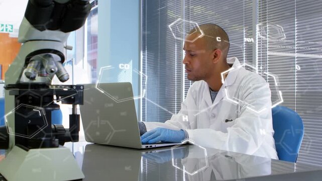Scientist typing on laptop in lab creating molecular overlay over microscope while analyzing data