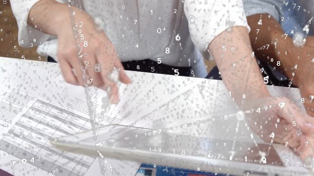 Two at table woman pointing, lifting tablet man marking bar chart numeric overlaying hands for biz