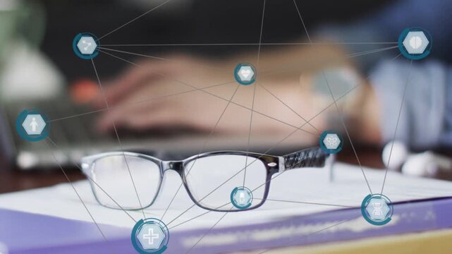 Hands typing starting teal network overlay around glasses on book, showing tech data connections