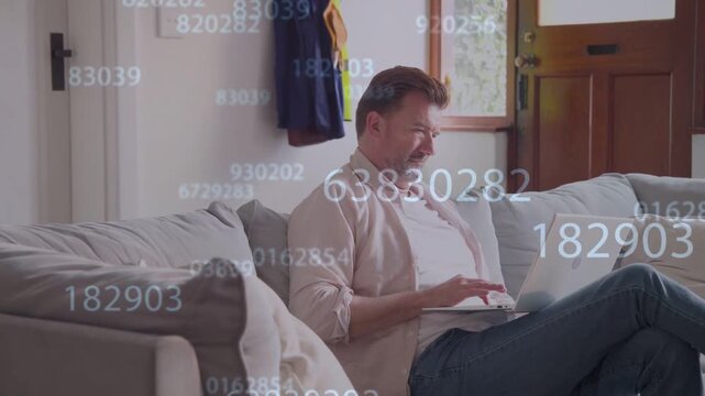 Mature man typing on laptop in living room, causing floating digits overlay while doing remote work