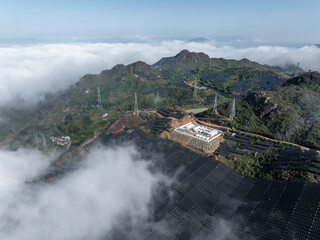 Fototapeta premium aerial view of solar power plant on mountain top surrounded by sea of clouds