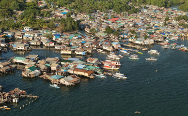Aerial drone view of the floating fishing village in Coron, Palawan, Philippines. Traditional stilt houses, colorful rooftops, and Filipino outrigger boats line the coastal waters © akturer